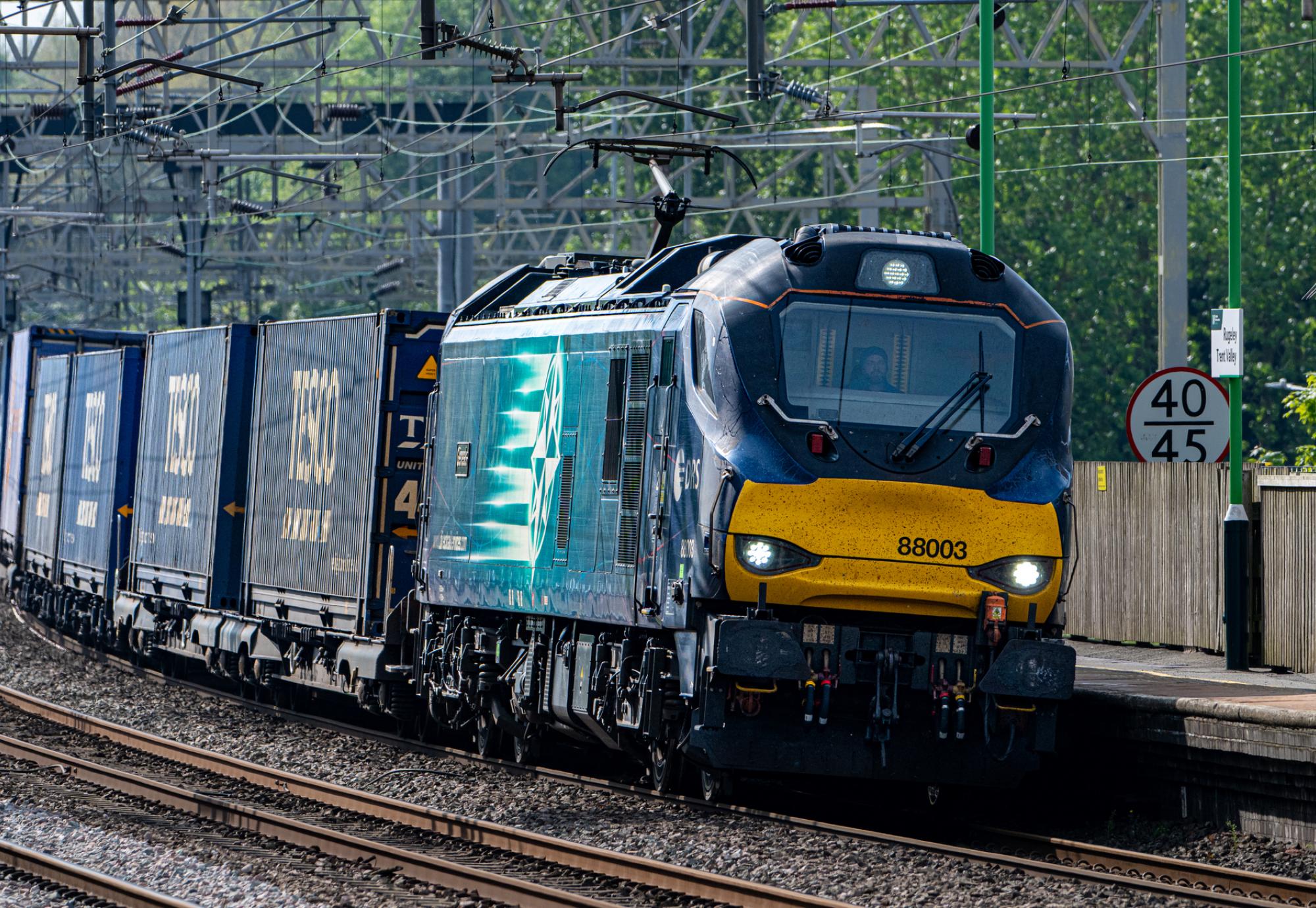 Freight train hauling containers through a UK station