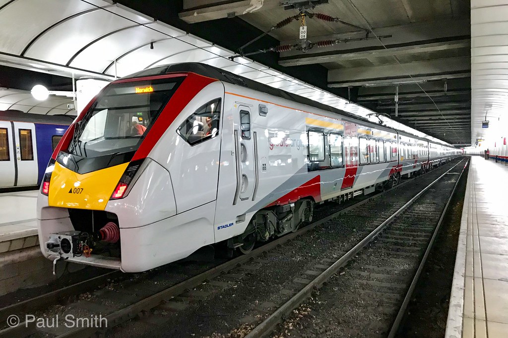 White, red and yellow Stadler passenger train at a station platform